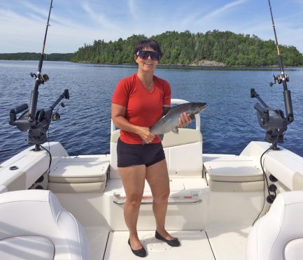 Claire Lespérance, la conjointe de Patrick, avec sa prise : une ouananiche. On peut voir les downriggers bien installés sur leur bateau.